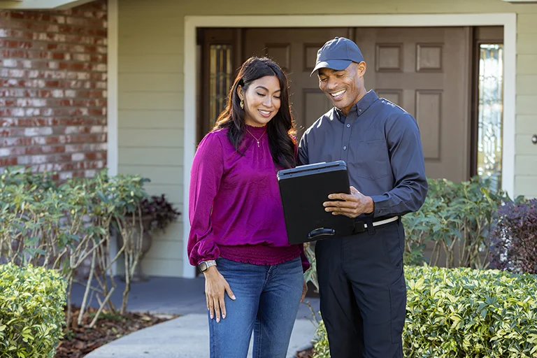 Exterminator speaking with home owner in front of house | All Good Pest Solutions serving Knoxville, TN